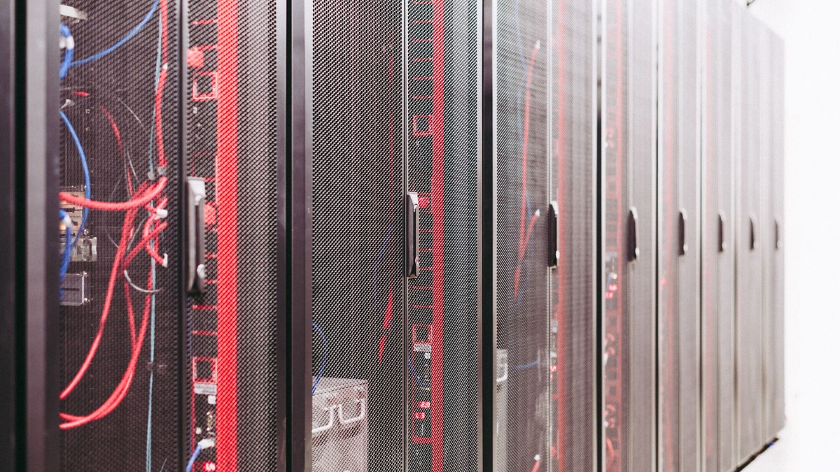Rows of black server racks with red and blue cabling in a data center