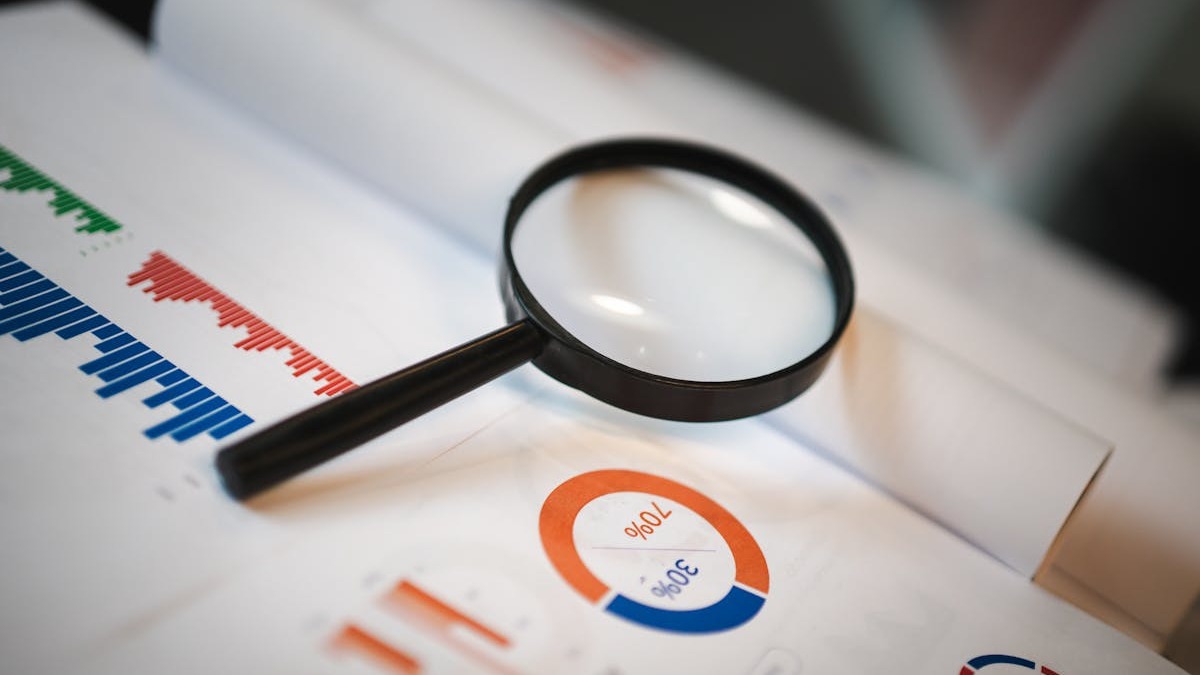 Magnifying glass examining financial documents and spreadsheet data