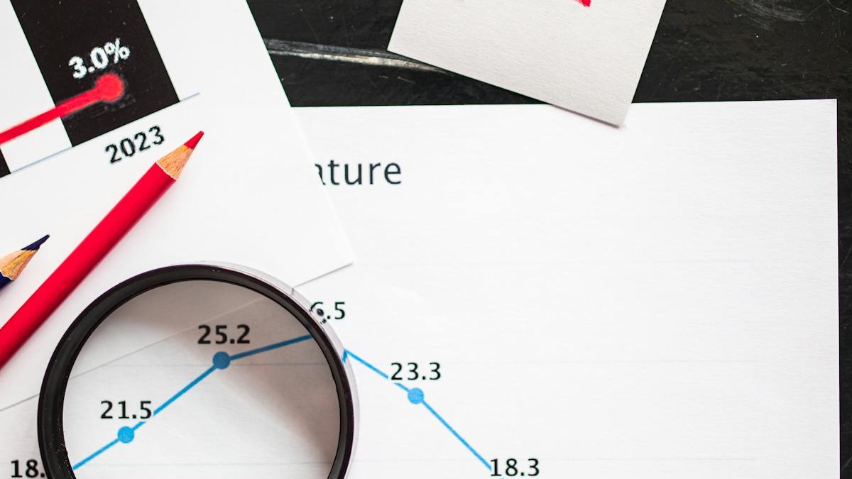 Magnifying glass analyzing printed financial charts with data patterns