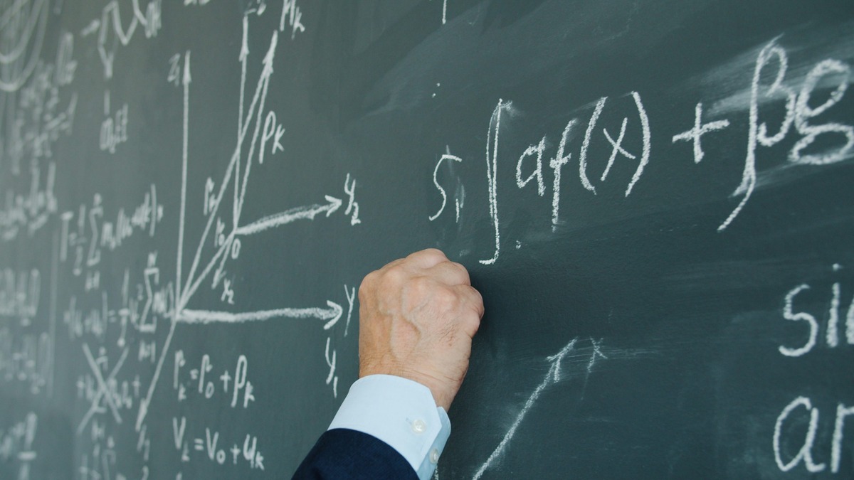 Handwritten mathematical formulas on a chalkboard in a university lecture hall