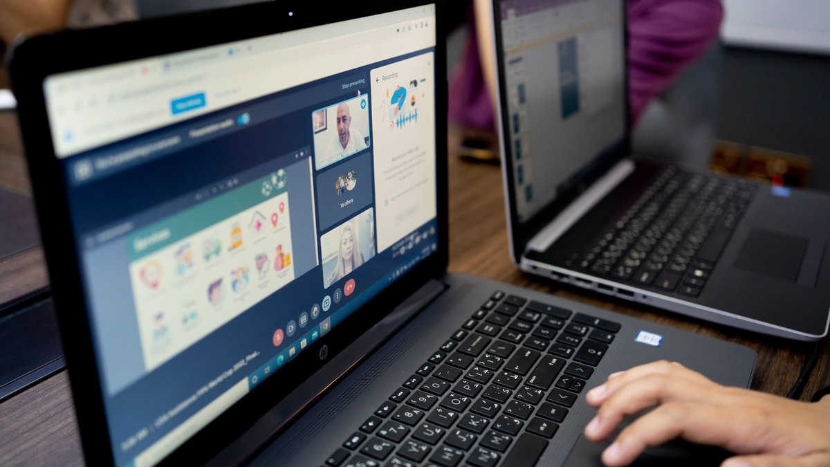 Multiple people participating in an online video call across several laptop screens
