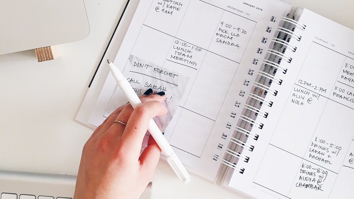 Open notebook with handwritten event notes and a pen on a desk