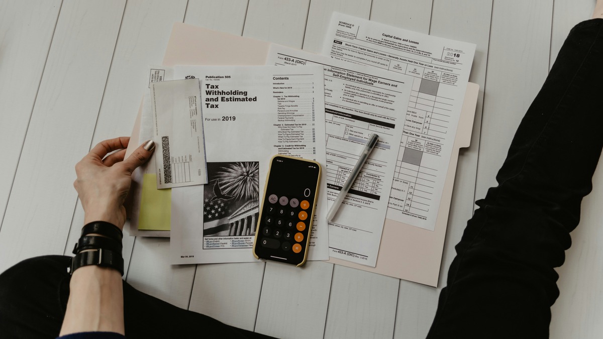 Person reviewing financial documents with a pen and calculator