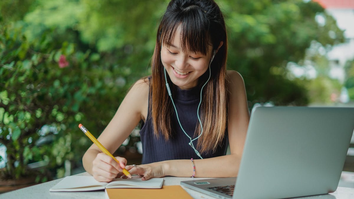 Young student learning with earphones and notebook