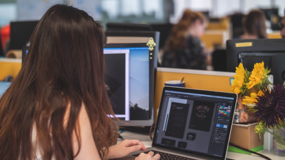 A person editing photos on a laptop in a bright workspace