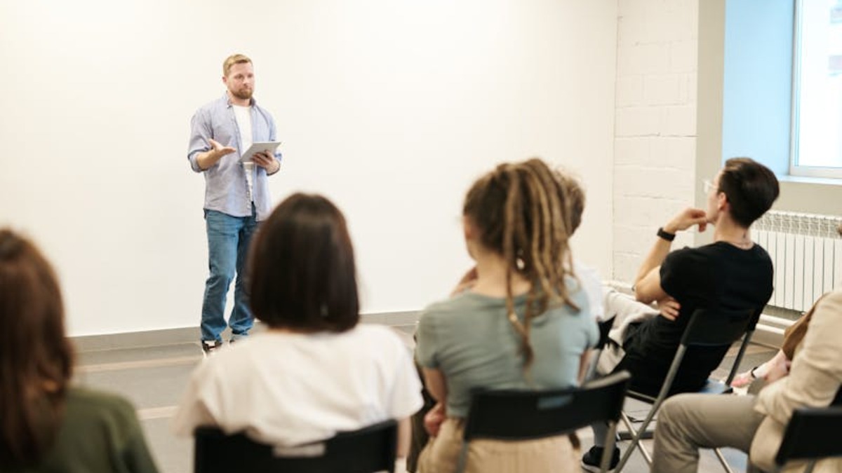 A presenter delivering a talk to a small audience, tablet in hand