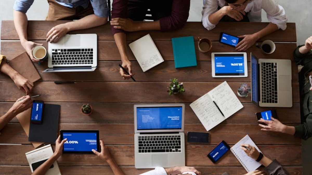 Overhead view of a collaborative team working with laptops and tablets showing presentation slides