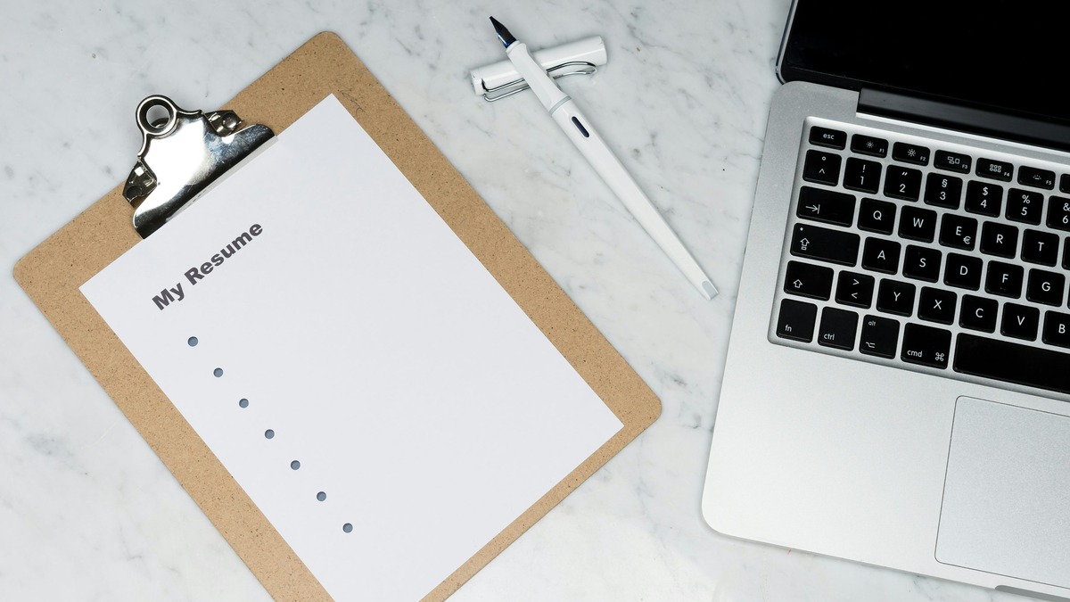A printed resume document beside a laptop on a desk