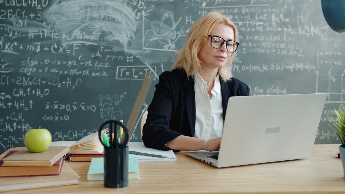 Teacher reviewing AI-generated lesson plans on a laptop in her classroom