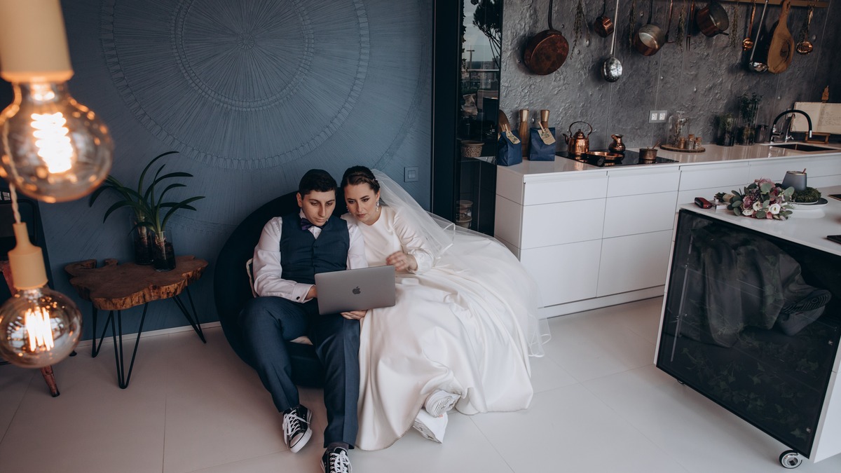 Bride and groom sitting together looking at a laptop screen
