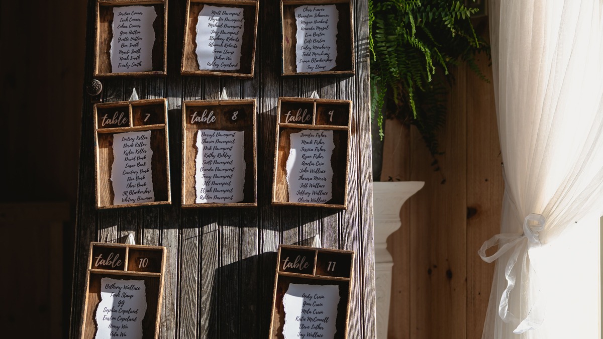 Rustic wooden wedding seating chart with framed table assignments on an easel