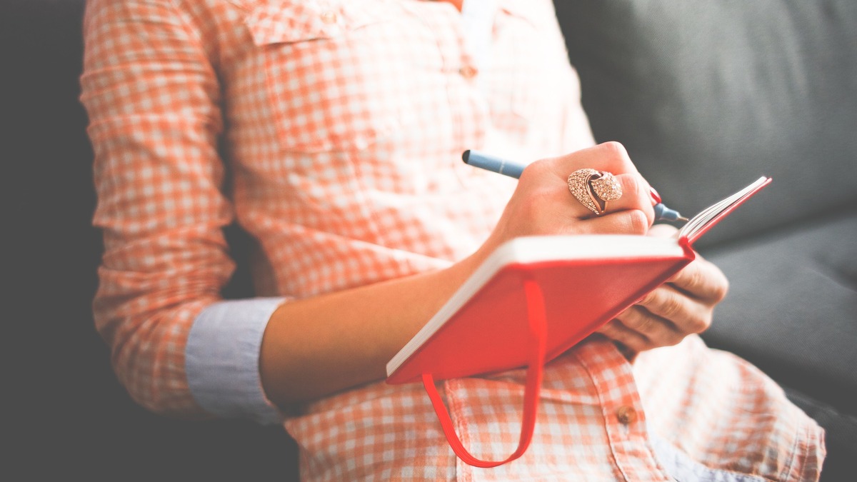 Close-up of a hand writing in a notebook while wearing a ring