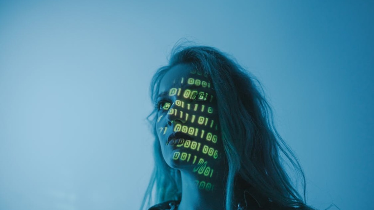 Binary code projected onto a person's face, illustrating digital identity and data surveillance