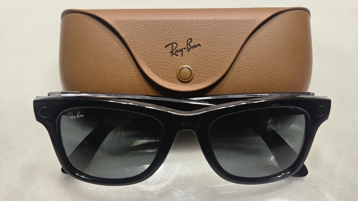 A pair of Ray-Ban Meta smart glasses resting in front of their charging case