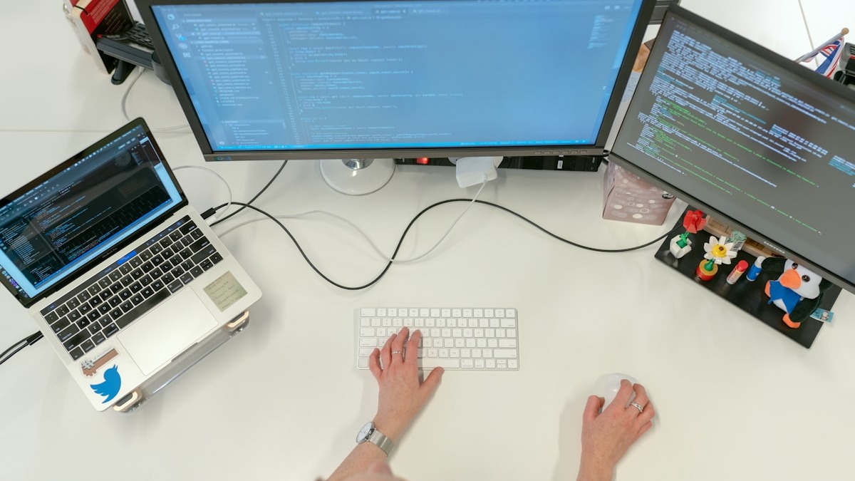 Developer using multiple monitors with code editors and terminal windows open