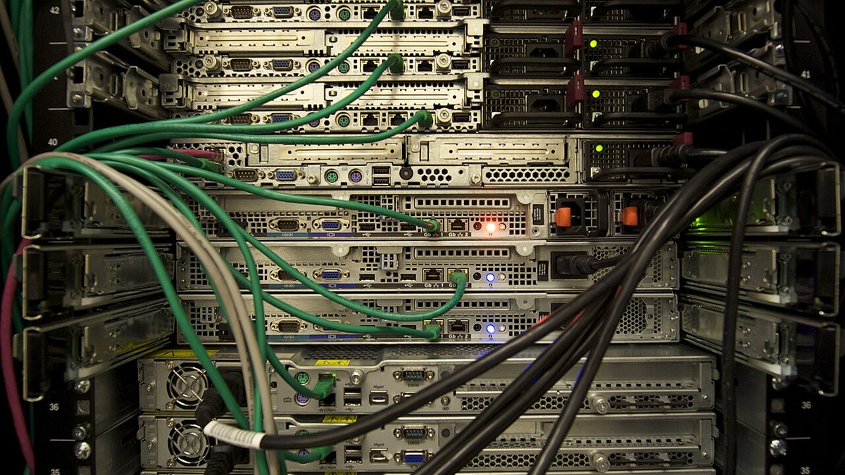 Rows of server hardware with tangled network and power cabling in a data center rack
