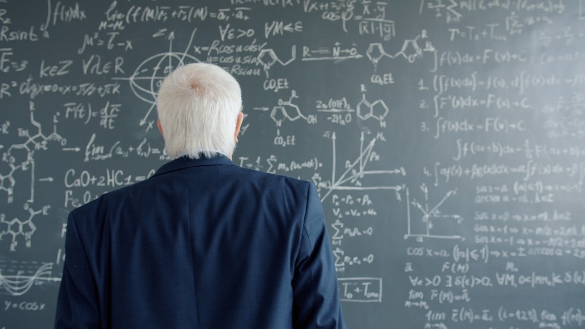 Researcher examining complex equations on a chalkboard, reflecting the extended proof-search behavior SU-01 was trained to perform