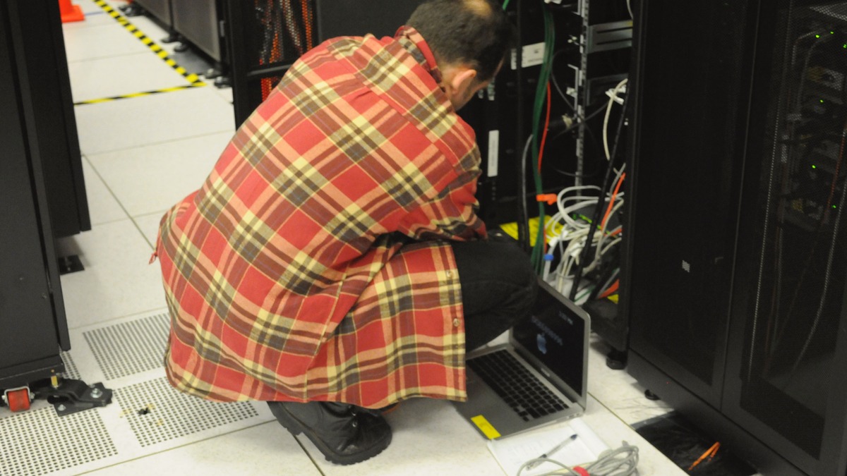 A technician working on server rack infrastructure at NERSC