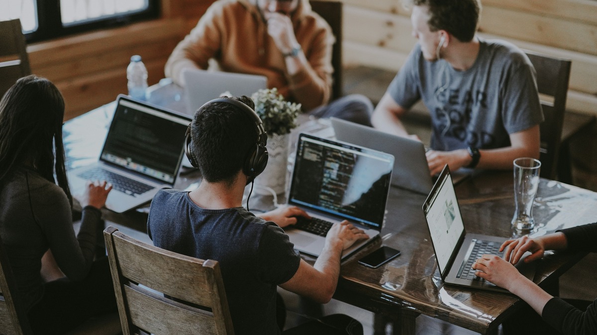 Team of engineers working together on laptops around a table