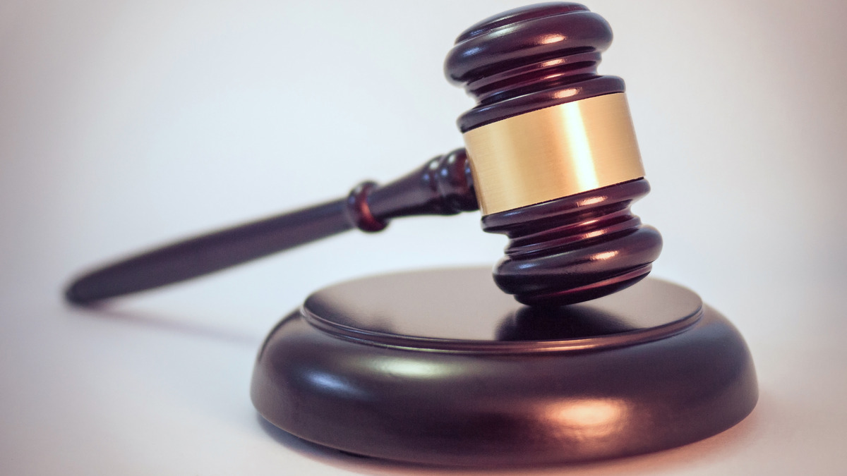 A wooden judge's gavel resting on its sound block against a plain background