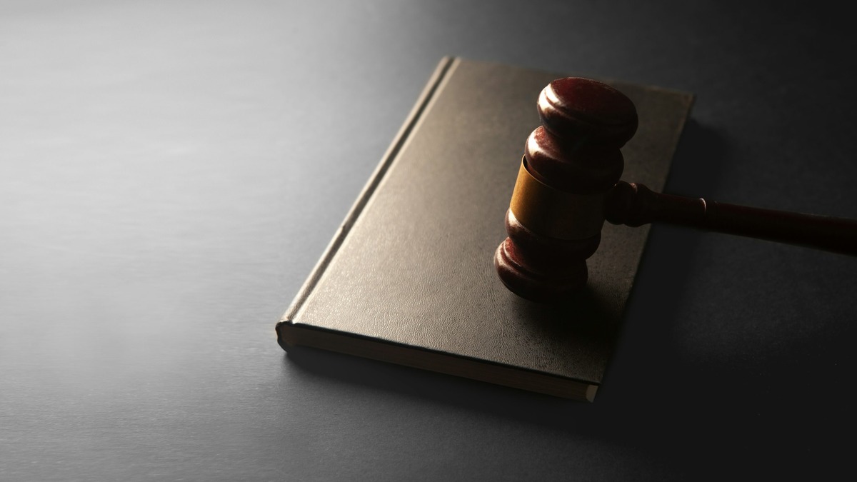 A wooden gavel resting on a closed book, symbolizing copyright enforcement and legal proceedings