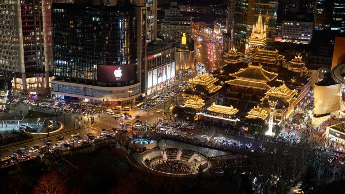 Apple's Jing'an store lit up at night in Shanghai, with the Jing'an Temple visible behind it