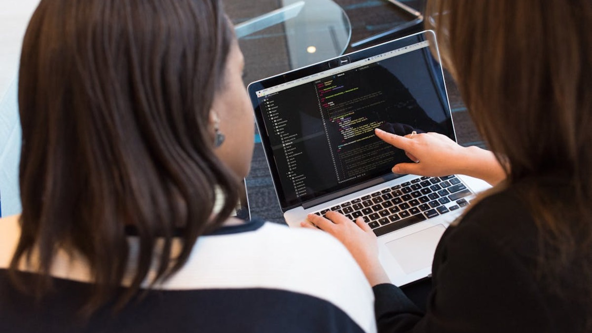 Two developers reviewing code on a laptop, illustrating the coding workflows where Chinese AI models have replaced US alternatives for many developer teams