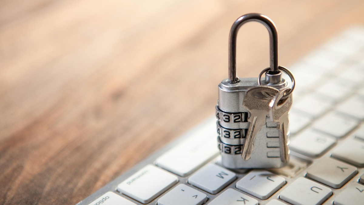 A padlock and a set of keys resting on a computer keyboard