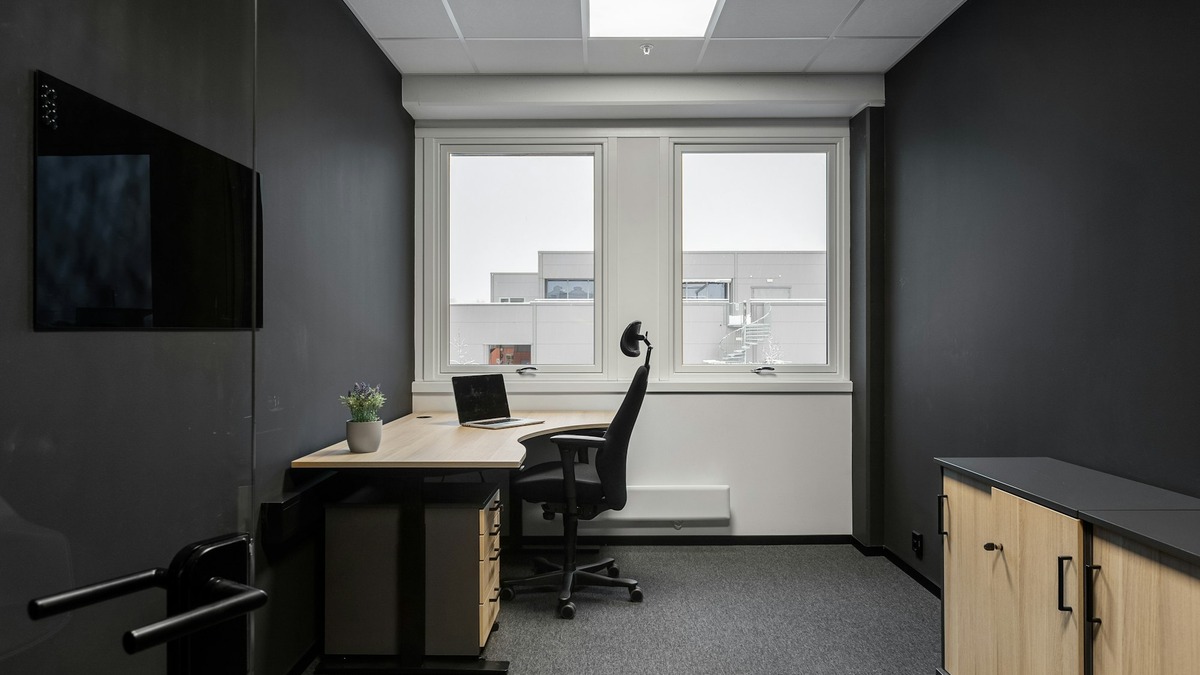An empty office desk and chair by a window