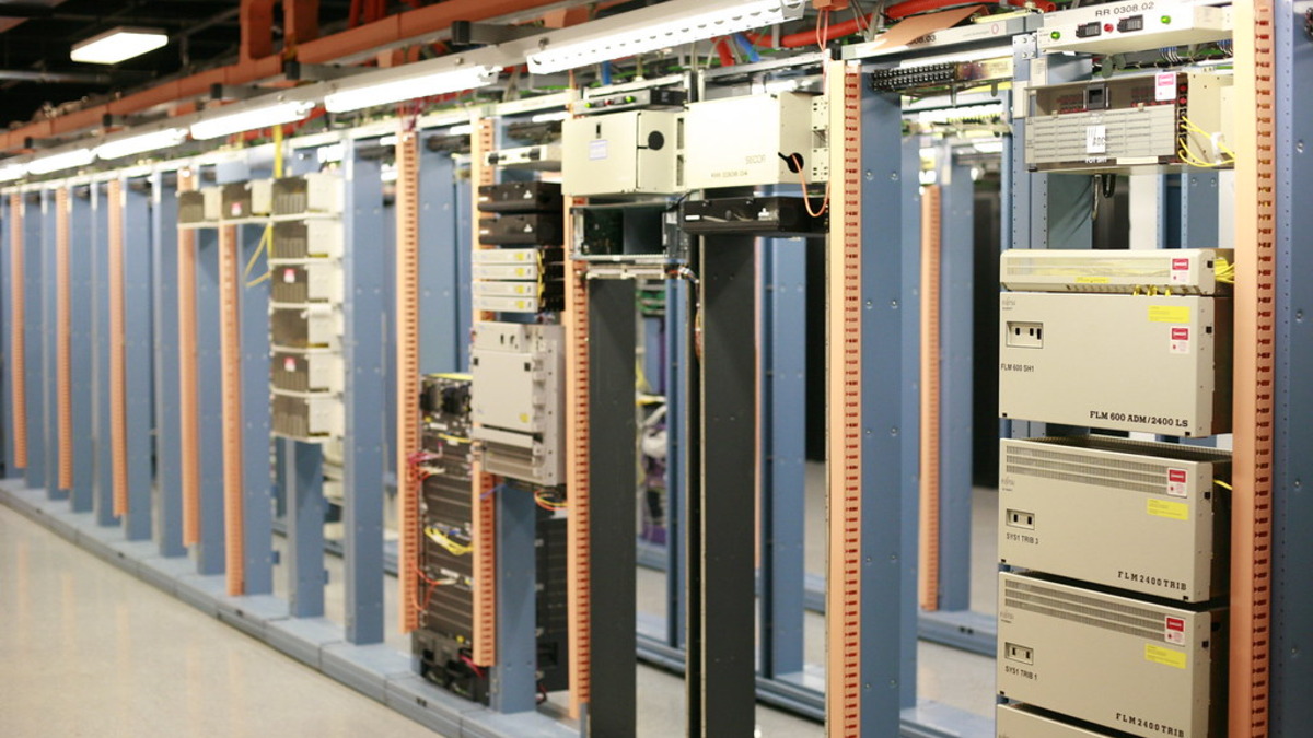 A server room interior showing dense rows of rack-mounted servers and network cabling
