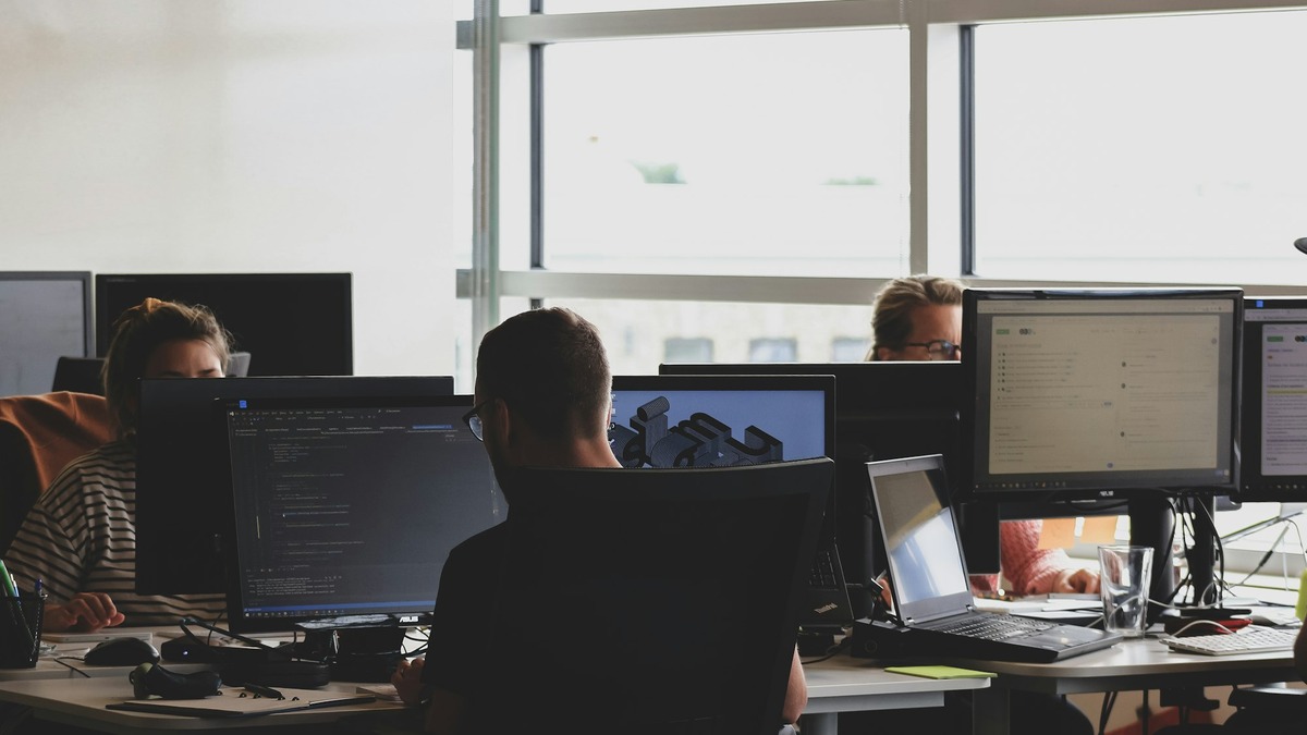 An employee working at multiple computer monitors in an office
