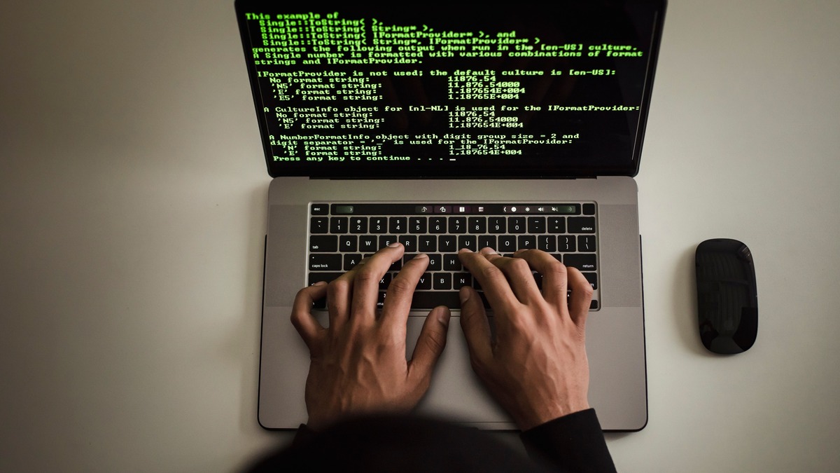 A developer's hands typing code on a laptop, overhead view