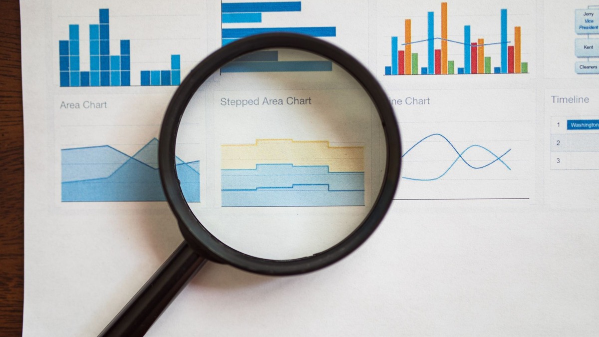 A magnifying glass held over printed bar charts and data visualizations