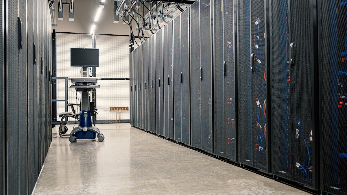 A data center corridor lined with server racks, illustrating the scale of infrastructure needed for AI inference
