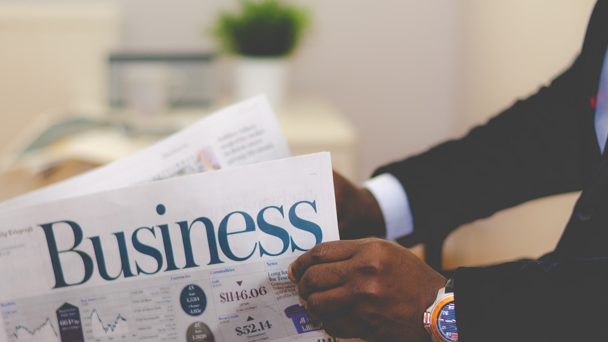 A business professional reads a newspaper showing financial data and market prices