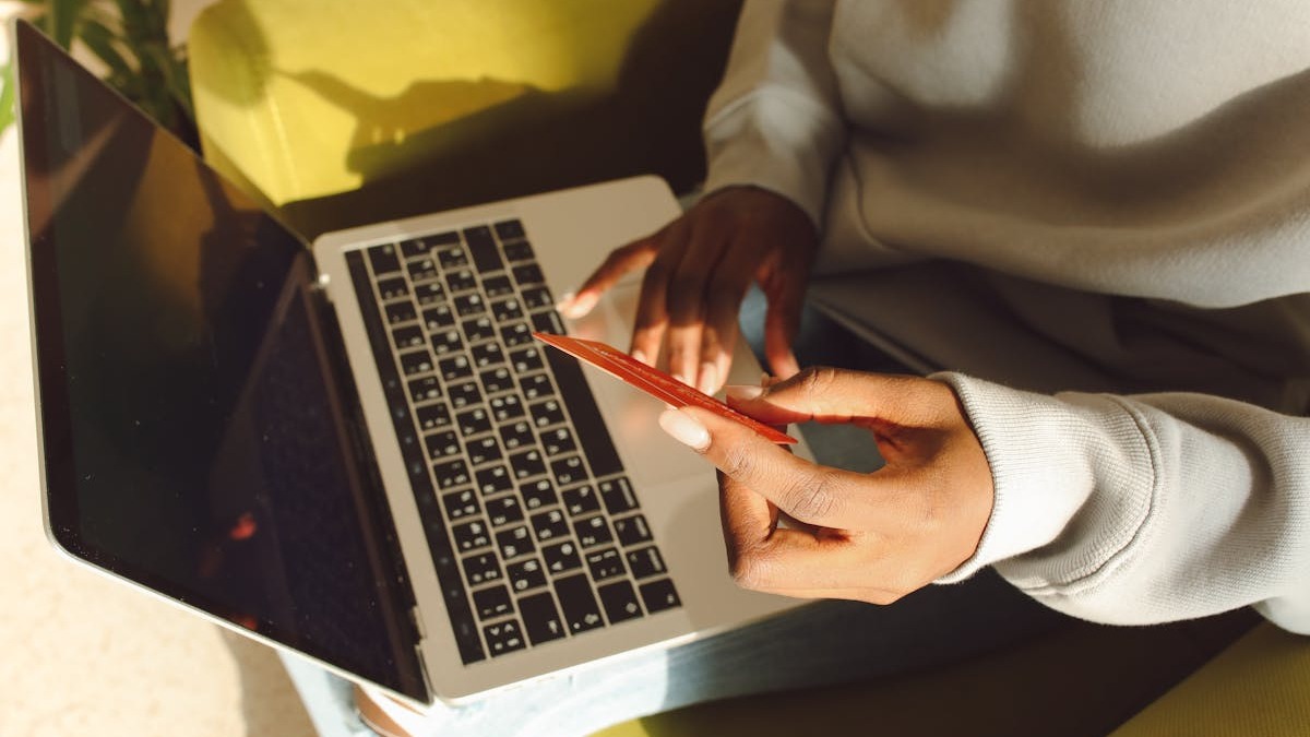 Person holding a credit card while shopping on a laptop