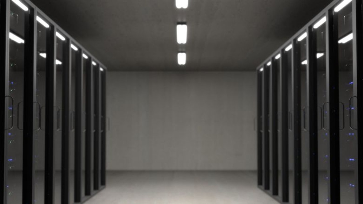 A large-scale data center with rows of server racks lit by status LEDs, representing the infrastructure that custom AI chips like Jalapeño are designed to power