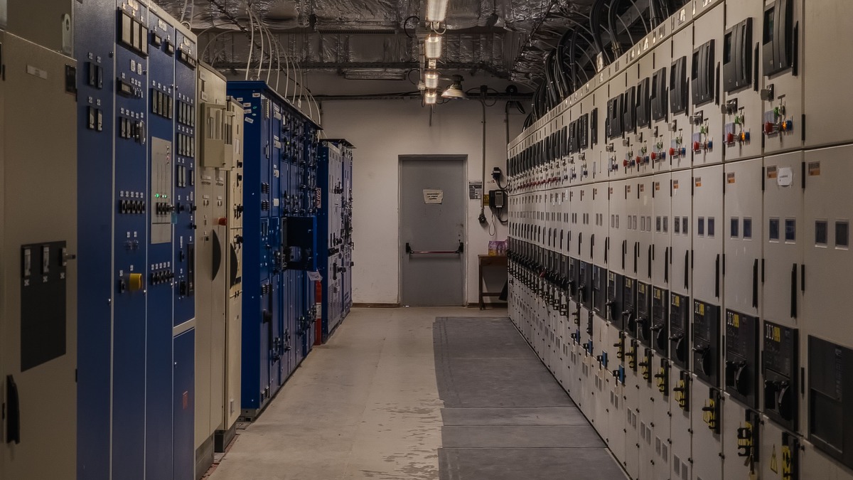 A row of tall electrical switchgear cabinets in an industrial substation control room