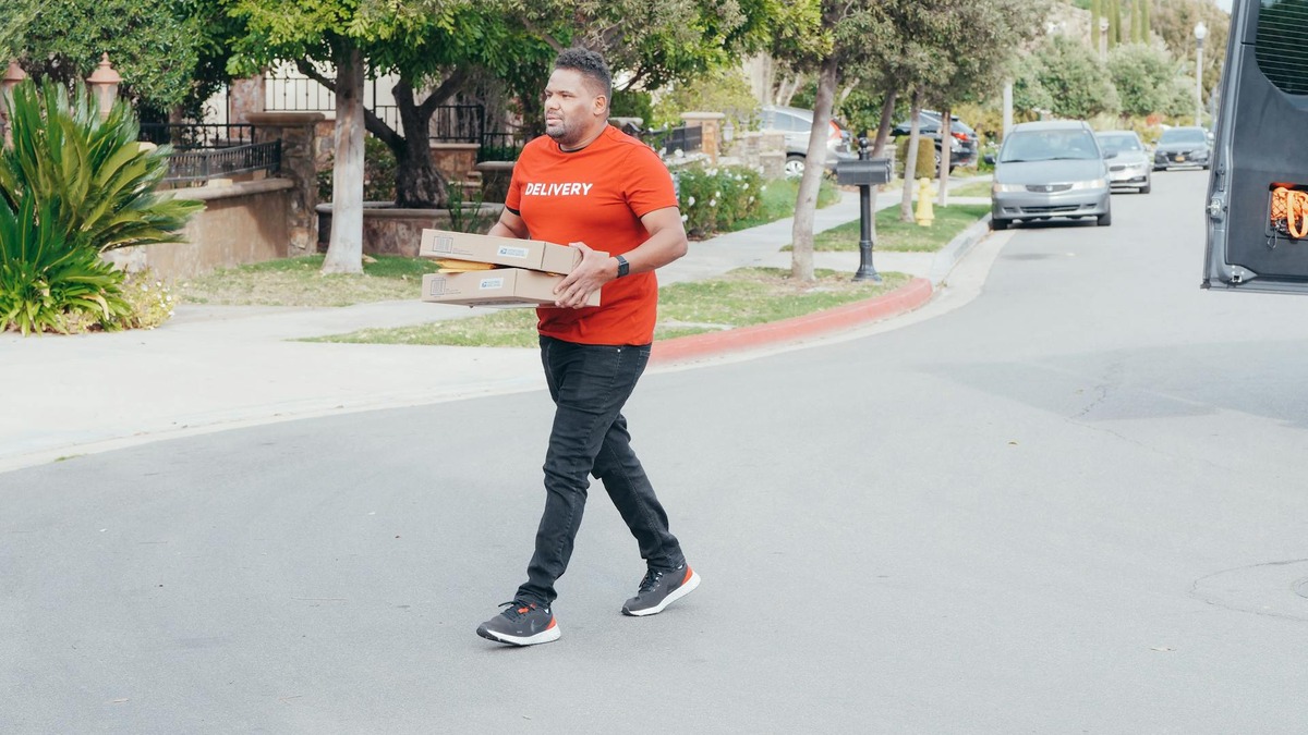 A delivery worker carrying packages down a street