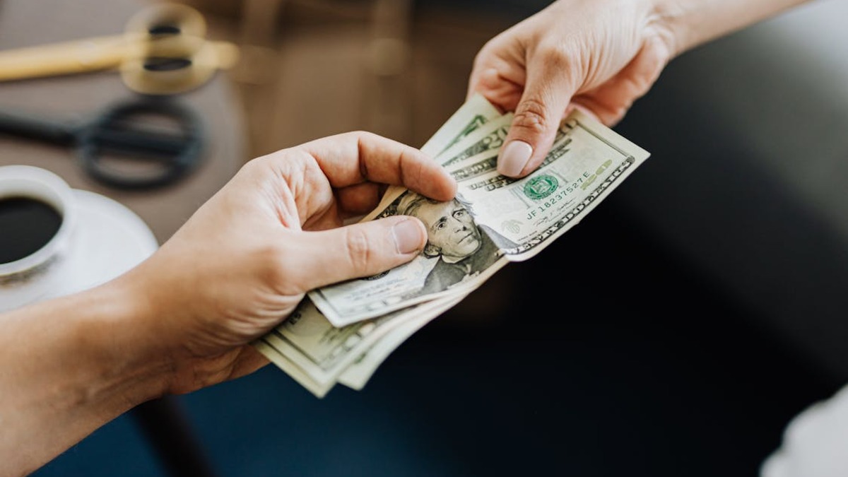 Two hands exchanging cash, representing financial transactions between parties