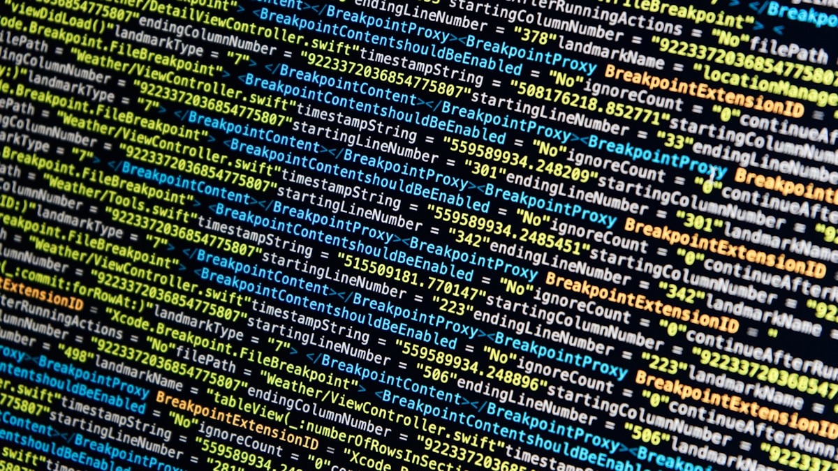 A developer workspace with a MacBook displaying code