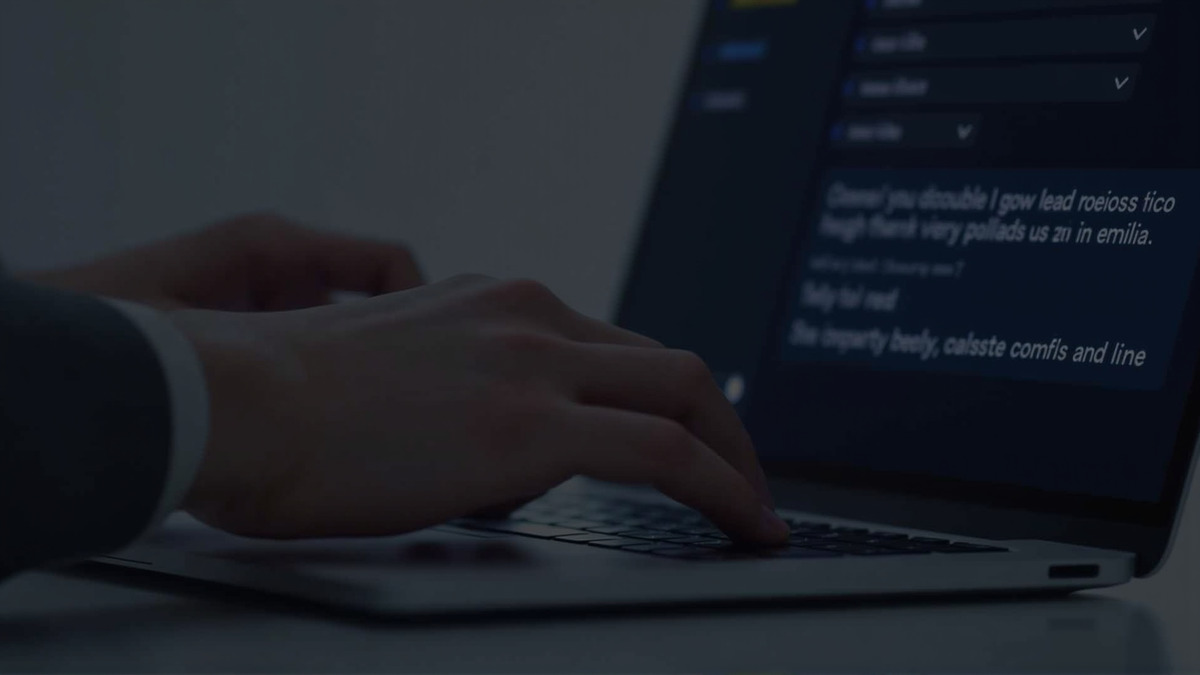 A close-up of a person's hands typing on a modern keyboard with a glowing screen in the background showing a chat interface