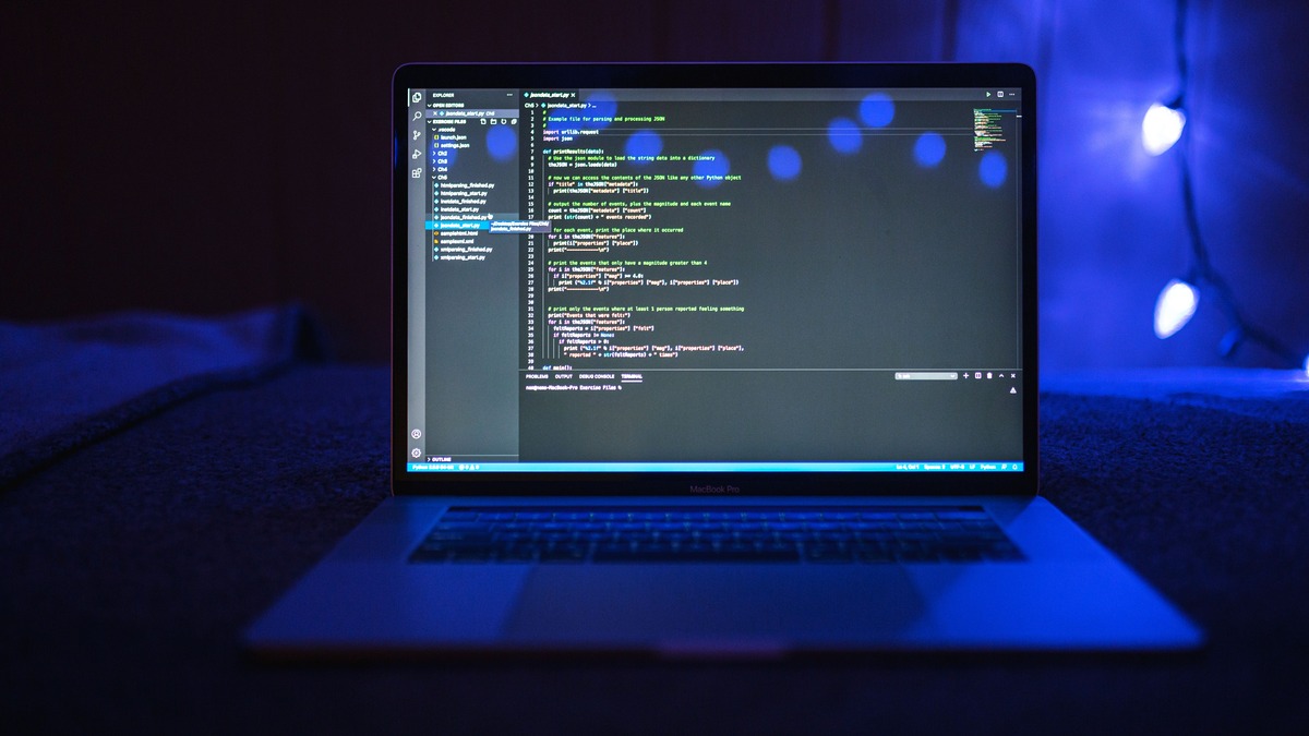 Close-up of programming code on a laptop screen in a dimly lit room