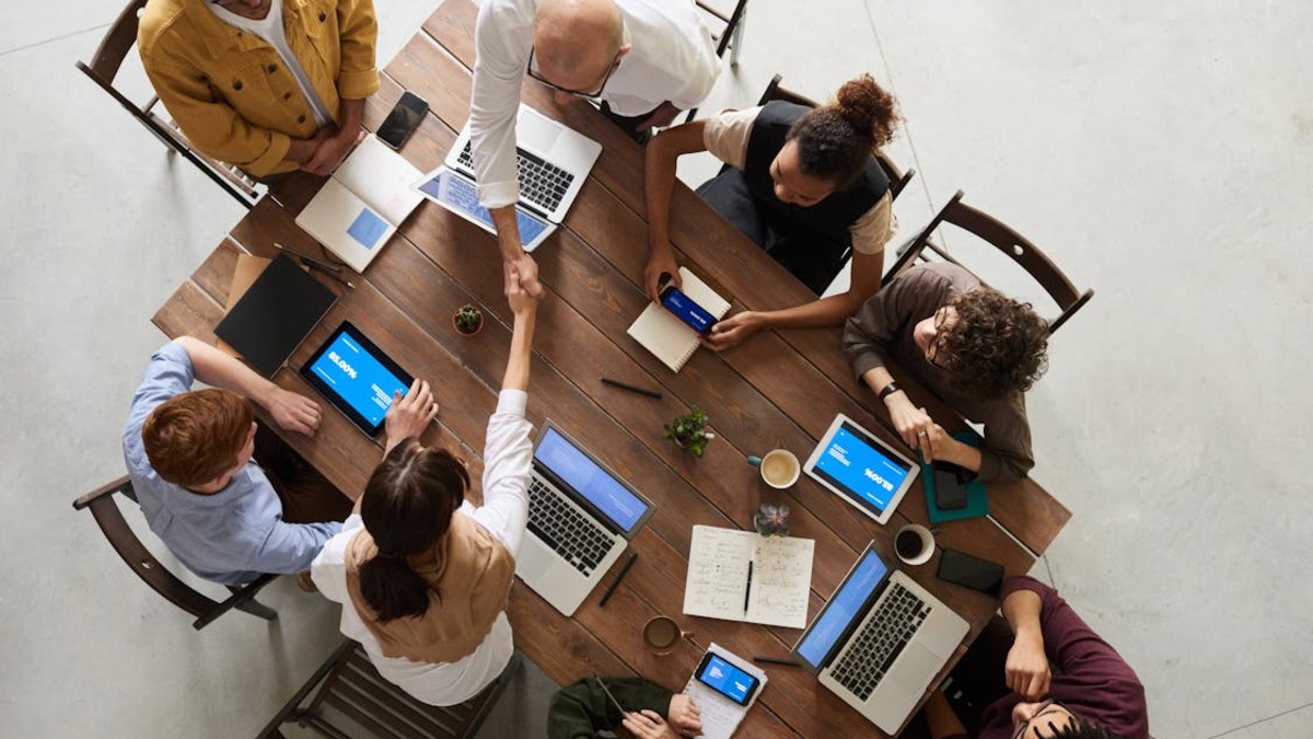 Enterprise team in a meeting room reviewing AI agent outputs on laptops