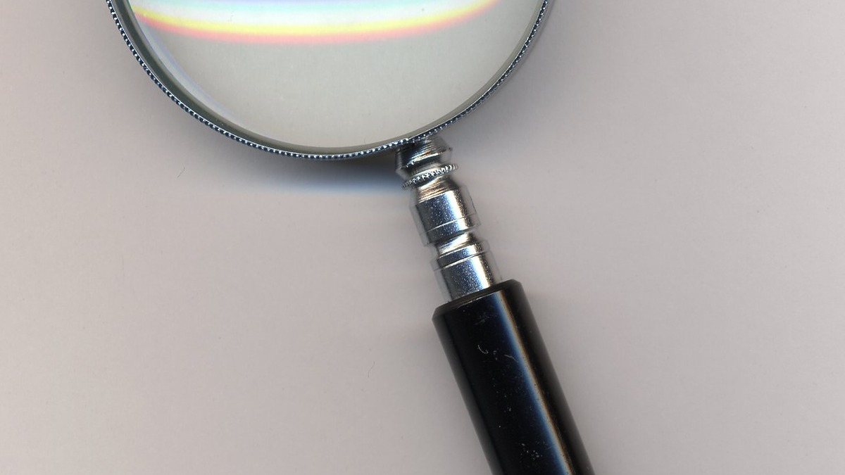 A magnifying glass examining documents, representing careful research synthesis