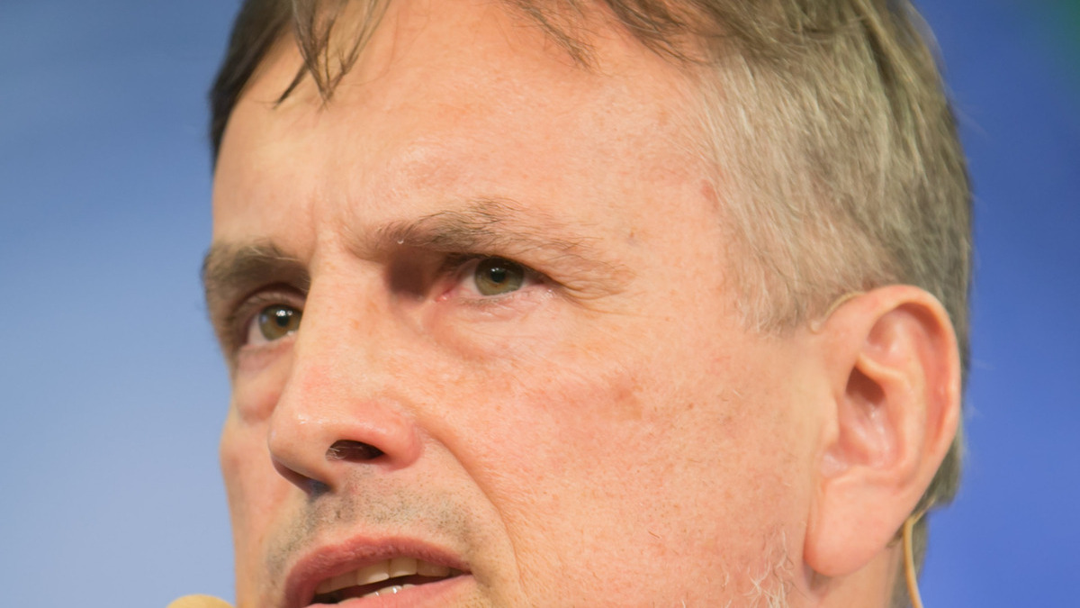 Portrait of Jürgen Schmidhuber speaking with a headset microphone