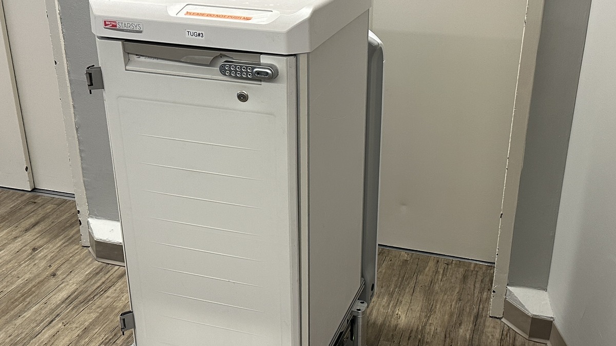 A hospital delivery robot navigating a corridor, with a sign indicating it has priority access to elevators