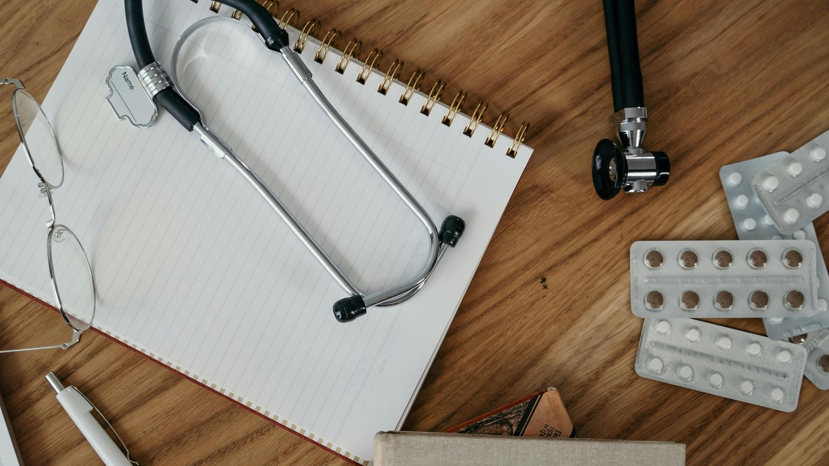 A stethoscope laid across a medical reference book on a desk
