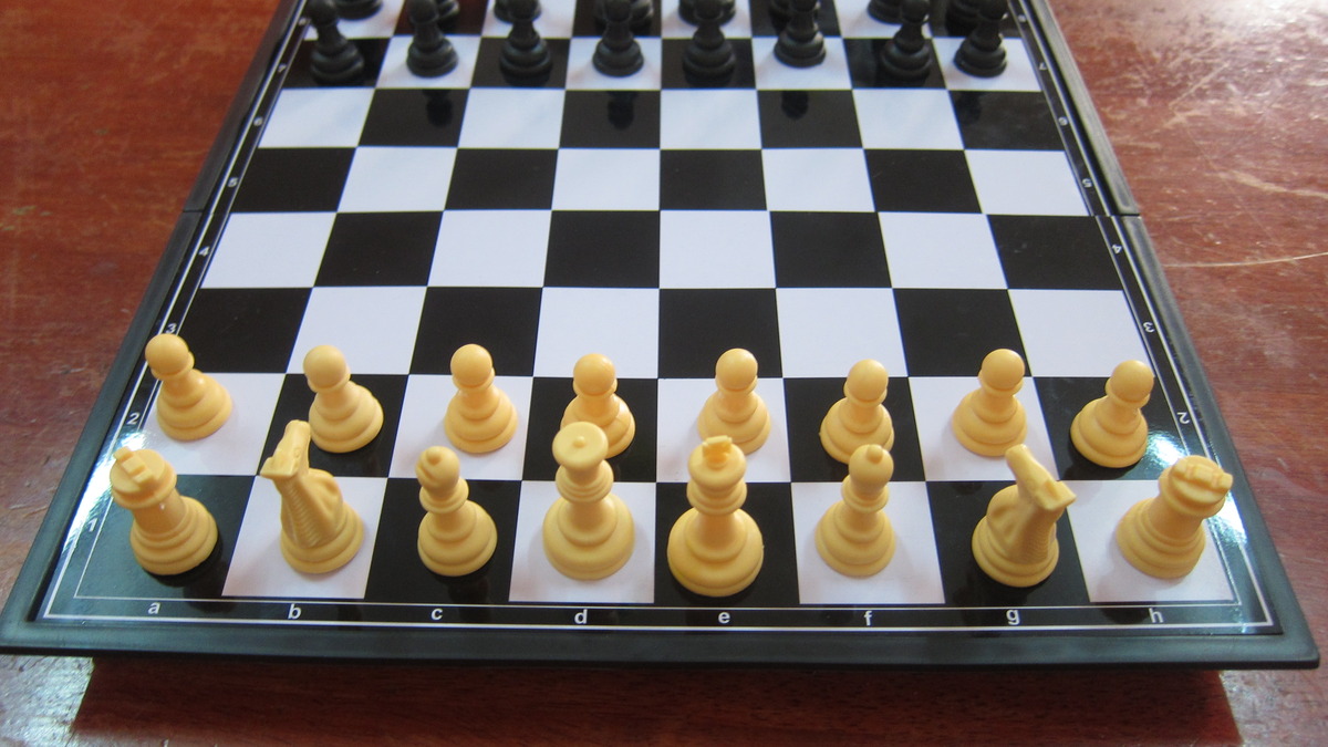 A chess board with pieces in the starting position, illustrating the game-theoretic structure of negotiation scenarios used to test LLM behavioral simulation