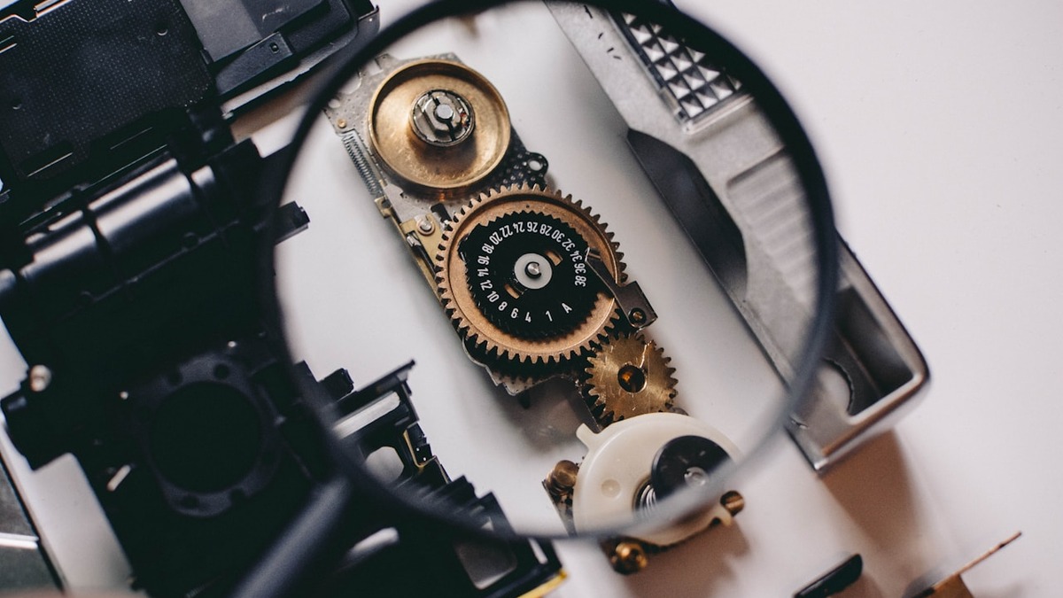 A person using a magnifying glass to examine a device component, representing the precision required in agent context management